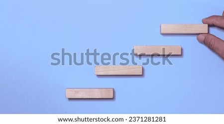 Business development process repository Hand holding a wooden block on a blue background Close up.with copy space.