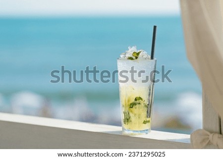 Glass of majito cocktail on terrace against blue sea. Cool drink on hot sunny day in cafe by the sea Royalty-Free Stock Photo #2371295025