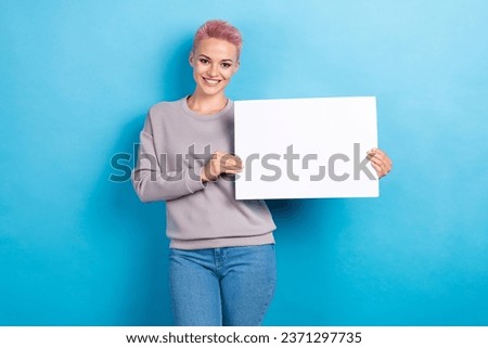 Photo of optimistic good mood adorable woman dressed gray sweatshirt hands hold placard empty space isolated on blue color background