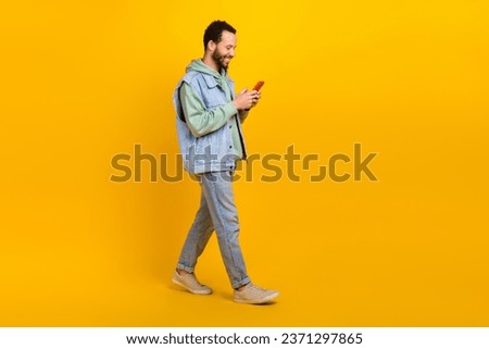 Full length body size picture of optimistic blogging hipster guy communicating writing message online isolated on yellow color background