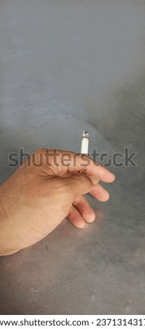 man hand holding a cigarette on metal background table