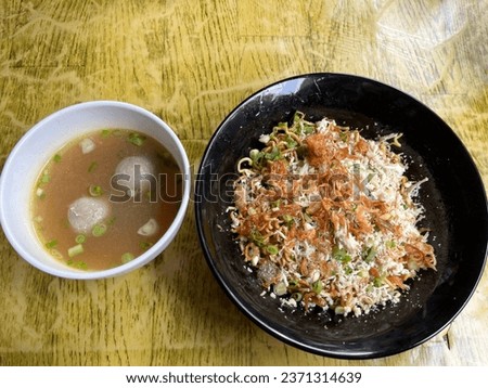 A bowl of chicken meatball noodles topped with fried onions and sliced ​​spring onions