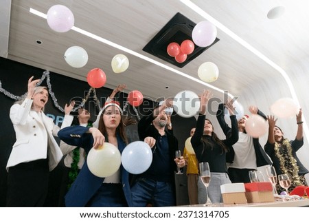A group of diverse business people and colleagues having fun together at a business New Year party. A teamwork celebration of a successful target. Confetti and balloons enjoyment.