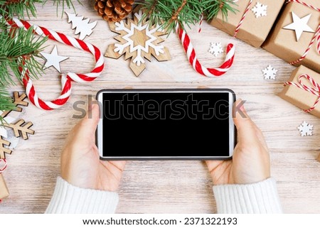 Woman using smartphone with blank screen, festive trumpery frame. Christmas gift search, online shopping, seasonal discounts and sale concept. Royalty-Free Stock Photo #2371322193