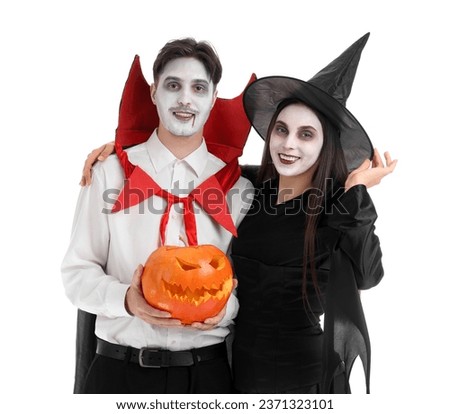 Young couple dressed for Halloween with pumpkin on white background