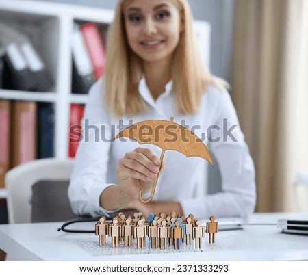 Smiling Business woman in hand holds a miniature umbrella in the hand of the topic of liability insurance