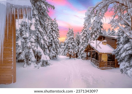 Snowy winter landscape in beautiful view of colorful sunset with wooden forest houses in cold snowy mountains at christmas time. Winter wonderland in snowy forest. Uludag mountain, Bursa city, Turkey.