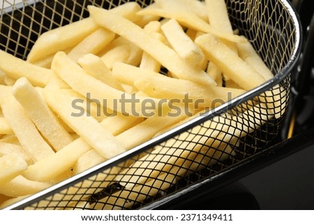 Uncooked french fries in metal basket, closeup Royalty-Free Stock Photo #2371349411