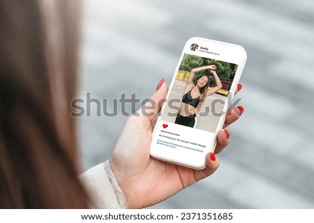Woman looking at beautiful model's photo on mobile phone with with a slim figure and athletic body. Social network concept