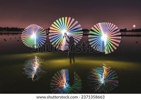 Beautiful lightpainting art above the water - woman draws 3 circles of light - Abstract Light Painting at night - Light Art Photography