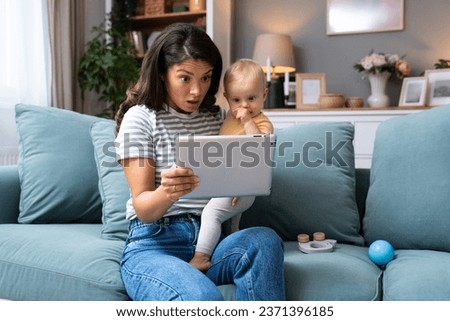 Freelance mother business woman sitting with newborn baby looking on tablet screen. Young mom holding child in one hand checking emails and statistic with other hand. Maternity leave business owner