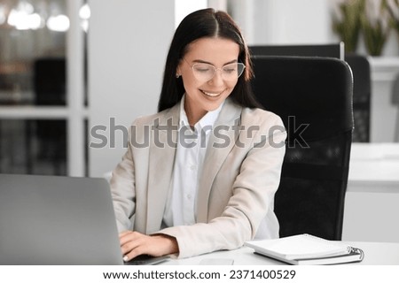 Happy woman using modern laptop at white desk in office