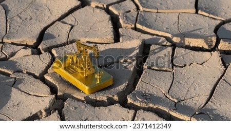 Golden model of an oil pump on cracked clay in the desert