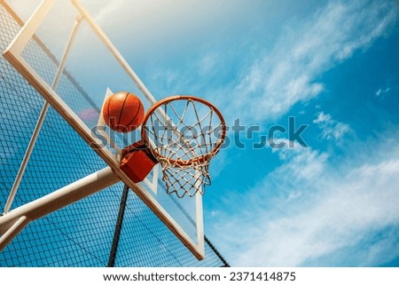 basketbol hoop with ball between hoop and backboard against beautiful blue sky on a sunny day  Royalty-Free Stock Photo #2371414875
