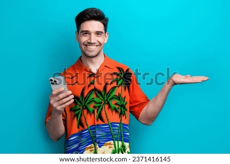Photo of funny young guy wear shirt hold arm product with iphone summer journey hotel mini bar discount isolated on blue color background
