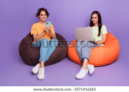 Full body photo of two colleagues cooperation together zone vip soft beanbags using netbook chat iphone isolated on purple color background