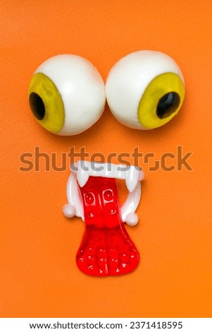 Spooky Halloween Sweets: Jelly Candy Faces with Gummy Eyes, Teeth, and Tongue on Orange Background