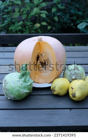 on the table lies a cut pumpkin next to vegetables