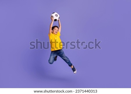 Full size photo of cute young schoolboy jumping catch football ball wear yellow clothes isolated on purple color background Royalty-Free Stock Photo #2371440313