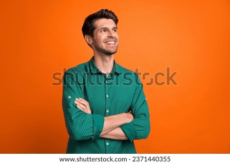 Photo of dreamy confident man dressed green shirt arms crossed looking empty space isolated orange color background