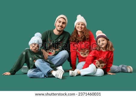 Happy family in warm sweaters sitting on green background