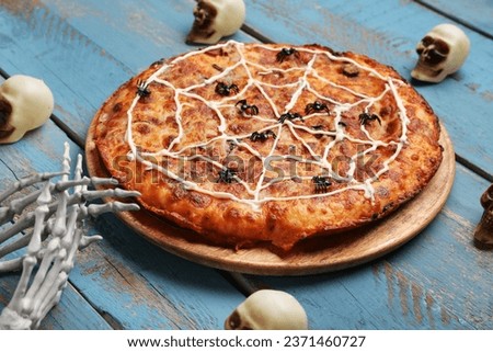 Board with tasty pizza and decorations for Halloween party on blue wooden background