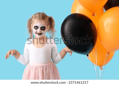 Little girl dressed for Halloween with balloons on blue background