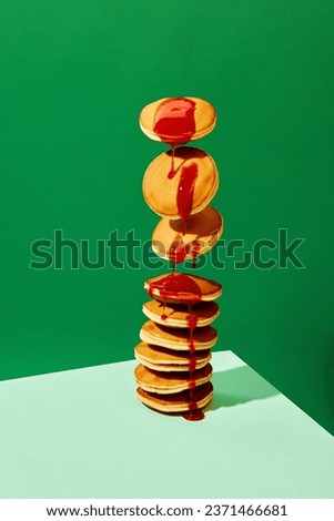 Food pop art photography. Close up. Flying sweet pancakes with delicious jam over green background. Vintage, retro 80s, 70s style, interior. Complementary colors. Concept of food, art, cooking. Ad