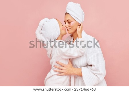 Motherhood. Loving mother and daughter in bathrobes and towels with eyepatches. Woman kissing her charming kid. Do beauty procedures together. Concept of beauty, spa treatment, natural cosmetic. Ad