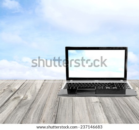 laptop on a wooden table on a background of the sky