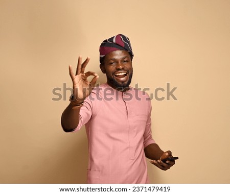 Portrait of an excited African man holding a smartphone, with his hands giving approval signs. mobile phone with empty space, copy space for Advertisement Royalty-Free Stock Photo #2371479419