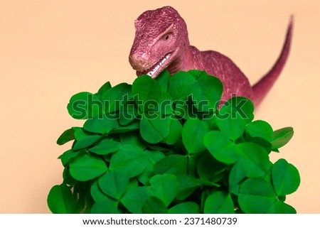 St. Patrick's Day happy dinosaur, a bouquet of clover in a bucket and gold coins on a beige background. Close up copy space