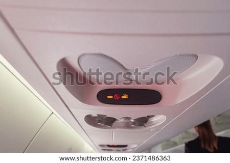 view of the overhead no smoking and buckle up seat belt indicator on the interior cabin of an airplane in flight