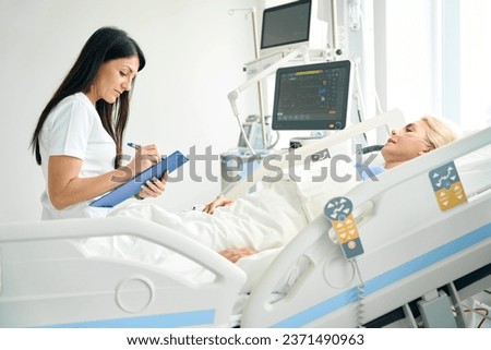 Pleasant nurse recording the patients vital signs