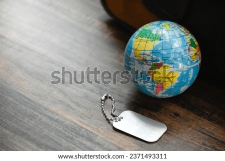 Earth Globe and Dog Tag on wood pattern work desk and soft sunlight background,Dog Tag empty,World and map of Americas,Top view with copy space,Desktop equipment,Concept of Travel and Work,Earth map.