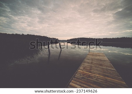 reflection of clouds in the lake with boardwalk and trees in background - retro, vintage style look