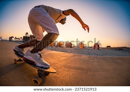 Surf skater training surfing moves near the beach at sunset. Royalty-Free Stock Photo #2371521913