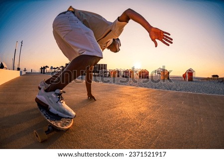 Surf skater training surfing moves near the beach at sunset. Royalty-Free Stock Photo #2371521917