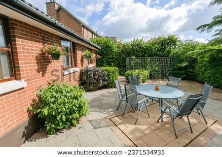 Modern patio with a table, chairs and barbeque behind a bungalow and sunroom. Royalty-Free Stock Photo #2371534935
