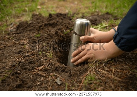 Bury a time capsule in the ground.Leave a message for the future in the ground.Hide a treasure with a child in the forest. Royalty-Free Stock Photo #2371537975