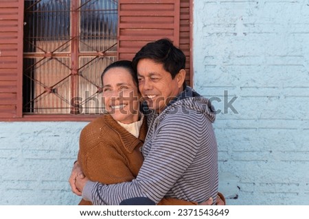 Cheerful Mature couplestanding and embracing each other outside the house. Togetherness, multi-generation family, support concept. Royalty-Free Stock Photo #2371543649