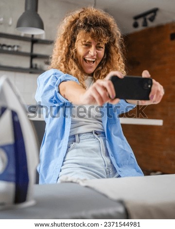 One adult young caucasian woman play video games on smartphone at home have fun while take a brake from housework real person leisure concept copy space