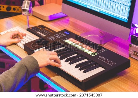 male musician, producer, arranger hands playing midi keyboard for recording music on desktop computer. music production concept