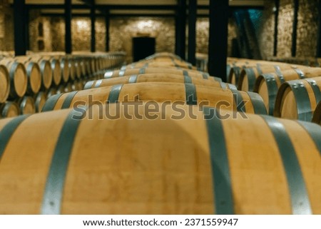 Wine or whiskey barrels stacked in wine cellar Royalty-Free Stock Photo #2371559947