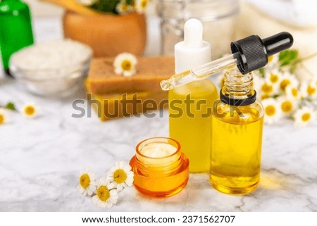 Chamomile spa. Composition with chamomile flowers, handmade soap, essential oil cosmetic bottle, body cream, scrub and sea salt on a white texture background. Relaxing beauty treatments.Copy space