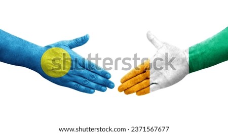 Handshake between Ivory Coast and Palau flags painted on hands, isolated transparent image.
