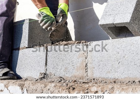 A builder holds a trowel during the construction of a wall made of aerated concrete blocks Royalty-Free Stock Photo #2371571893
