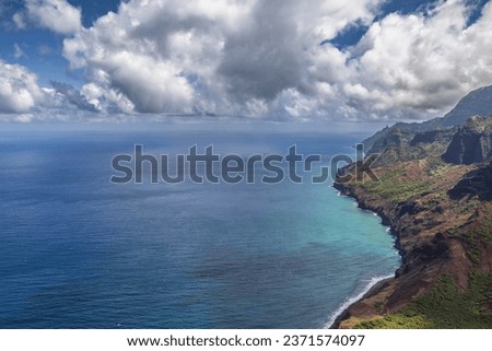 Glistening waters along the shore of Kauai Hawaii with heavy rain clouds above