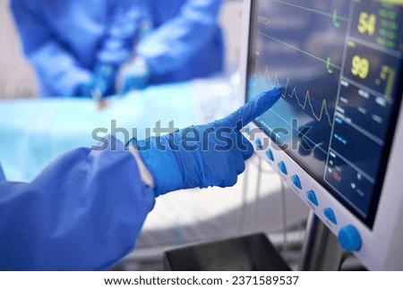 Nurse, monitor and electrocardiogram in surgery, cardiology and check on vitals in operation. Doctor, healthcare and procedure with medical equipment for cardiovascular health, screen and hospital Royalty-Free Stock Photo #2371589537