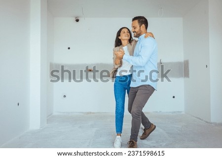 Dancing Couple Happy With Apartment Choice. Relocation, real estate, rent concept. Happy and Excited Young Couple Look Around In Wonder at their Newly Purchased